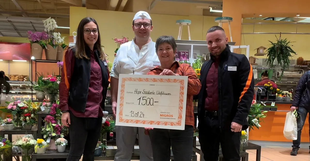 Vier Menschen blicken in die Kamera. Eine Frau hält einen Check über 1500 Franken.